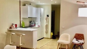 A modern kitchen with white cabinets, a dining area with a table and chairs, and a large rug on the floor. - Brand new apartment with amazing view and close to everything (Sestriere)