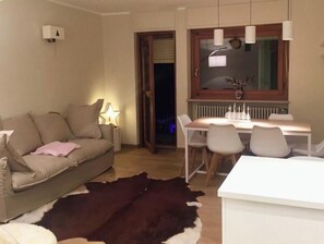 Un salon comprenant un canapé, une table à manger avec des chaises, un tapis en peau de vache et une fenêtre donnant sur un paysage agréable.