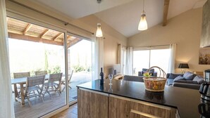 Uma sala de estar ampla, com uma ilha grande de madeira, uma mesa de jantar com cadeiras, um sofá e uma máquina de café.