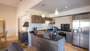 Cozinha moderna com ilha central, eletrodomésticos embutidos e iluminação pendente.