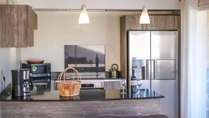 Cozinha moderna com ilha central, eletrodomésticos de aço inoxidável e armários de madeira.