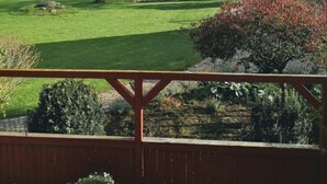A view from a deck overlooking a well-maintained lawn with a pond, trees, and a small wooden structure. - Hos Mette (Borkop)