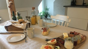 A breakfast setup with a variety of foods and drinks on a table, including cheese, fruits, and beverages. - Hos Mette (Borkop)