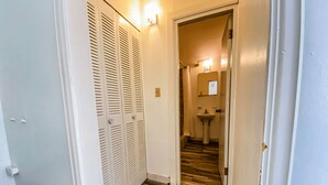 A hallway with a wooden floor, white walls, and a white door with louvered shutters. - Gladioli 1206 - That's all Puerto Rico (Ponce Pueblo)