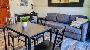 A living room with a sofa, a dining table, and chairs. There is a potted plant on the table. - Gladioli 1206 - That's all Puerto Rico (Ponce Pueblo)