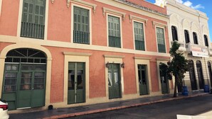 A row of buildings with green doors and windows, some with balconies. - Gladioli 1206 - That's all Puerto Rico (Ponce Pueblo)