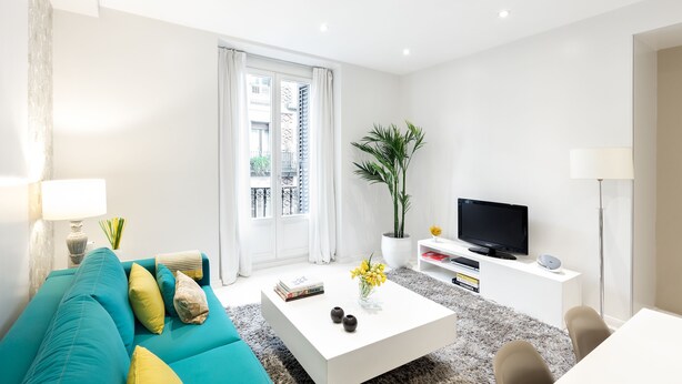 A modern living room with a teal sofa, white coffee table, and a flat-screen TV on a white stand. - CARRETAS APARTMENTS MADRID 202 (MADRID)