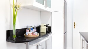 A modern kitchen with white cabinets, a black countertop, and a coffee machine. - CARRETAS APARTMENTS MADRID 202 (MADRID)