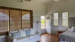 A bedroom with a bed, a white sofa, and a ceiling fan. - Abreeze Studio: Stunning Hilltop Villa in Destino (Puerto Ferro)