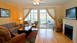 A living room with a sofa, chairs, a coffee table, a fireplace, a television, and a ceiling fan. - Luxury & Location in New Buffalo - Downtown, Close to Beach, Private Pool (New Buffalo)