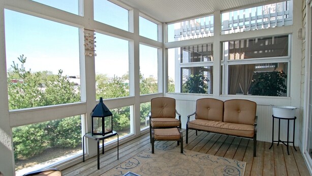 A sunroom with large windows, a ceiling fan, and a wooden floor. - Luxury & Location in New Buffalo - Downtown, Close to Beach, Private Pool (New Buffalo)