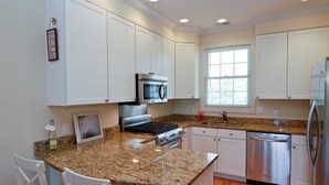 A kitchen with white cabinets, granite countertops, stainless steel appliances, and a window providing natural light. - Luxury & Location in New Buffalo - Downtown, Close to Beach, Private Pool (New Buffalo)