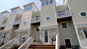 A row of townhouses with multiple balconies, a front porch, and a brick foundation. - Luxury & Location in New Buffalo - Downtown, Close to Beach, Private Pool (New Buffalo)