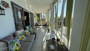 A sunlit balcony with a sofa, potted plants, and a table. - Villa Pinos de Alhaurin Torre Malaga (Alhaurin de la Torre)
