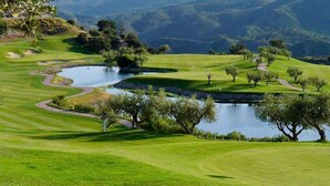A golf course with a pond, trees, and rolling hills in the background. - Villa Pinos de Alhaurin Torre Malaga (Alhaurin de la Torre)