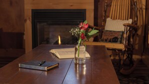 A wooden table with a book, a pen, and a vase with flowers. - Immaculate mountain cabin with awe inspiring sunrise and mountain views (Ripton)