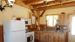 A kitchen with wooden cabinets, a refrigerator, a stove, and a sink. - Immaculate mountain cabin with awe inspiring sunrise and mountain views (Ripton)