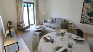 Un comedor con una mesa redonda para cuatro, un sofá, una silla y una lámpara.