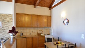 Una cocina con armarios de madera, estufa, lavaplatos y una mesa de comedor con sillas.