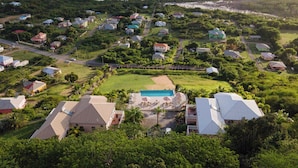 Vue aérienne d’un quartier résidentiel avec des maisons, une piscine et une plage.