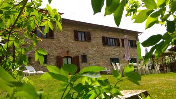 Un edificio in pietra con diverse finestre e una zona relax esterna coperta.