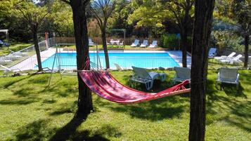 Relax by the serene pool surrounded by lush greenery and lounge chairs, or unwind in the hammock.