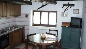Una cocina con armarios de madera, estufa, pileta y ventana.