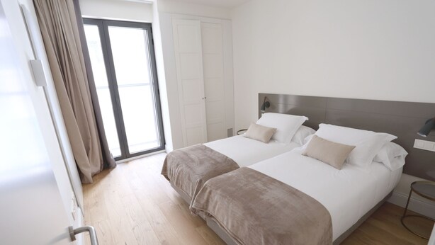 A double bed with a headboard, a bedside table, and a large window with curtains. - Comfort apartment, warmth in the center of Girona. WIFI & AIR. (Girona)