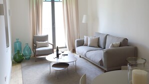 A modern living room with a sofa, armchair, coffee table, and decorative vases. - Comfort apartment, warmth in the center of Girona. WIFI & AIR. (Girona)