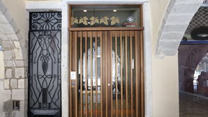 A wooden gate with a metal decorative design, a sign above it, and a stone wall to the left. - Comfort apartment, warmth in the center of Girona. WIFI & AIR. (Girona)