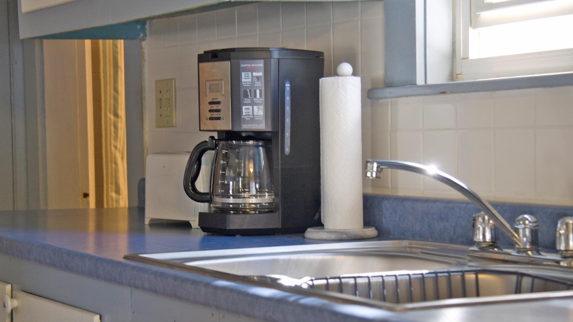 A kitchen with a coffee maker, a sink, and a window.