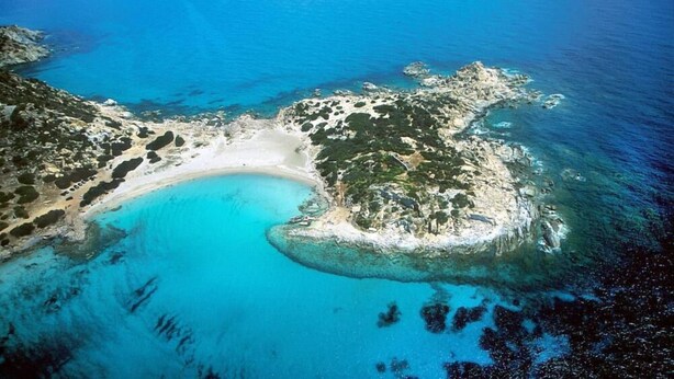 An aerial view of a coastal area with a sandy beach, clear blue waters, and rocky terrain. - Three-room Full Optional Villasimius Country, Climate, Box, Terrace. (Villasimius)