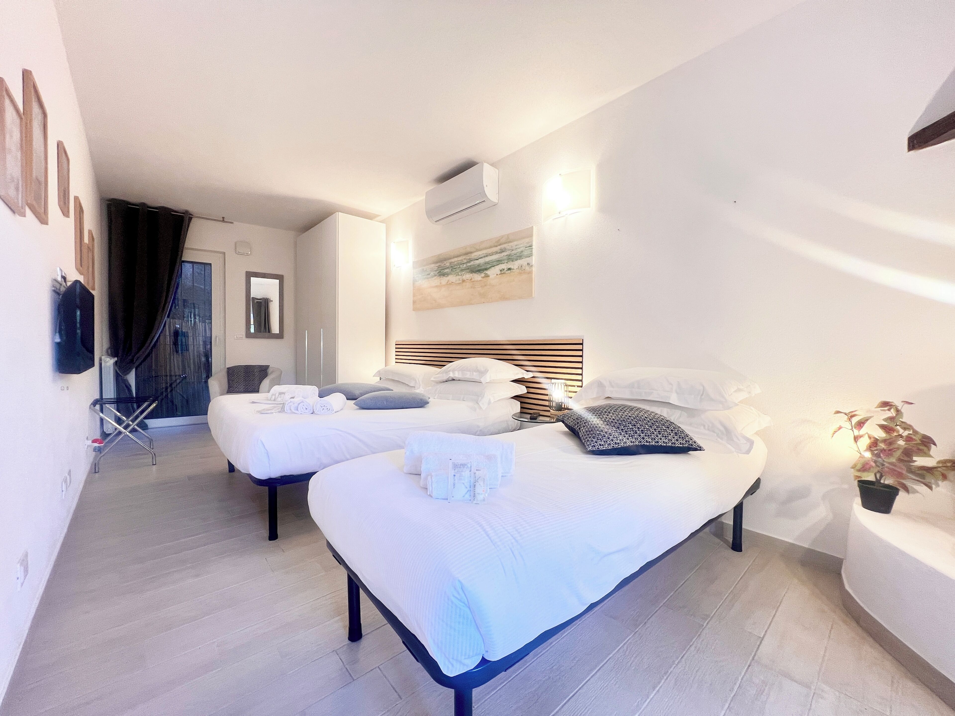 A hotel room with two beds, a flat-screen TV, a ceiling fan, and a potted plant.
