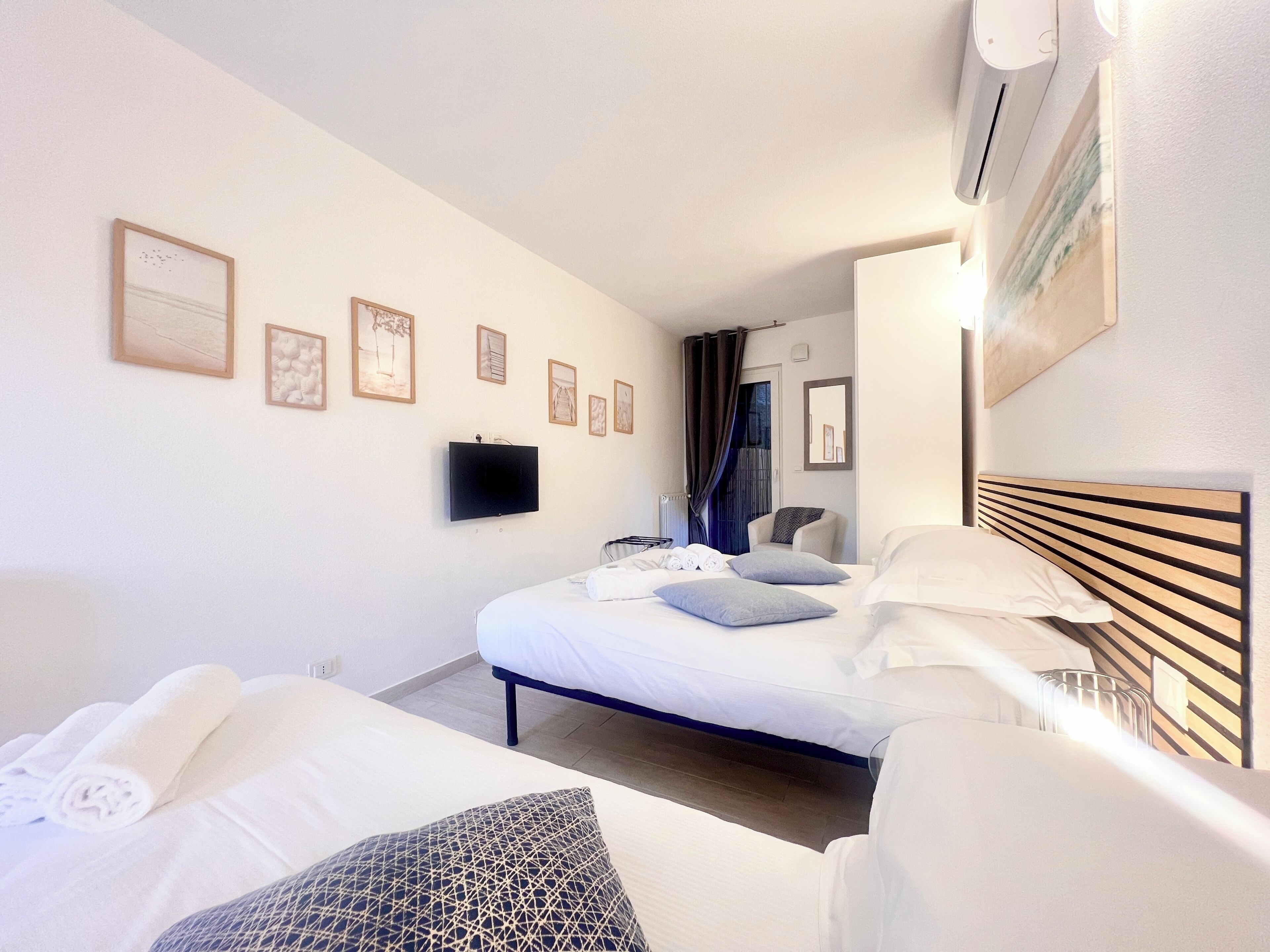 Habitación de hotel con dos camas, un televisor de pantalla plana y una silla.