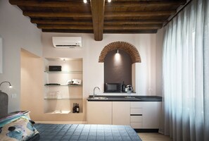 A compact kitchen with a built-in microwave, sink, and wine bottles on the wall.