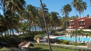 A resort with a pool, palm trees, and a building with a red facade.