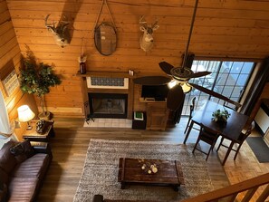 View of living room from upstairs open loft bedroom-  wood burning fireplace