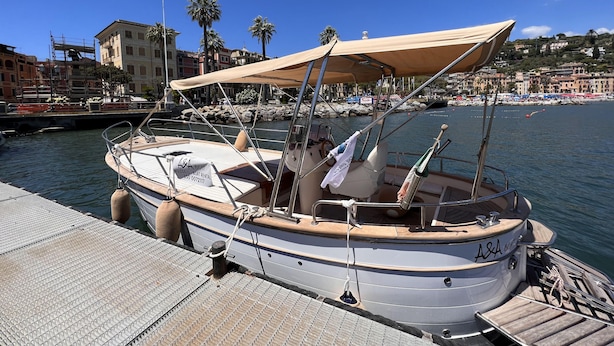 A boat docked at a pier with a covered seating area, a steering wheel, and a rope tied to a bollard. - Il Rifugio di San Massimo, Rapallo (Rapallo)