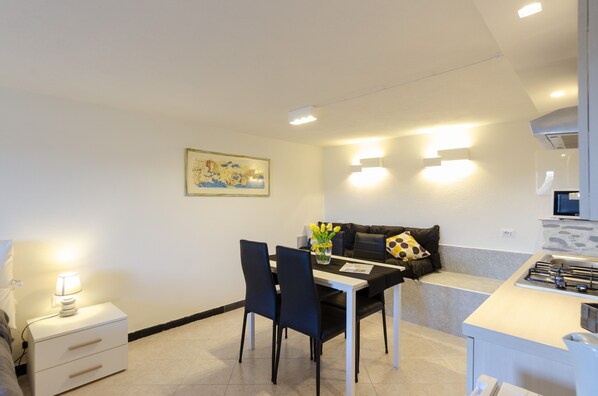 A modern kitchen with a dining area, a sofa, and a painting on the wall.