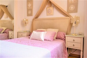 Une chambre à coucher comprenant un lit, des tables de chevet, un miroir et des panneaux décoratifs sur les murs.