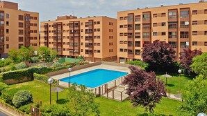 Ein modernes Mehrfamilienhaus mit Schwimmbad, umgeben von gepflegten Gärten und Bäumen.