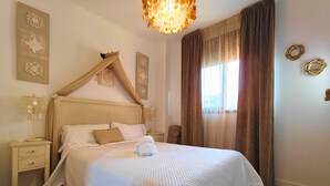 Ein ordentlich bezogenes Bett mit Baldachin, ein Nachttisch mit Lampe und ein Fenster mit Vorhängen.