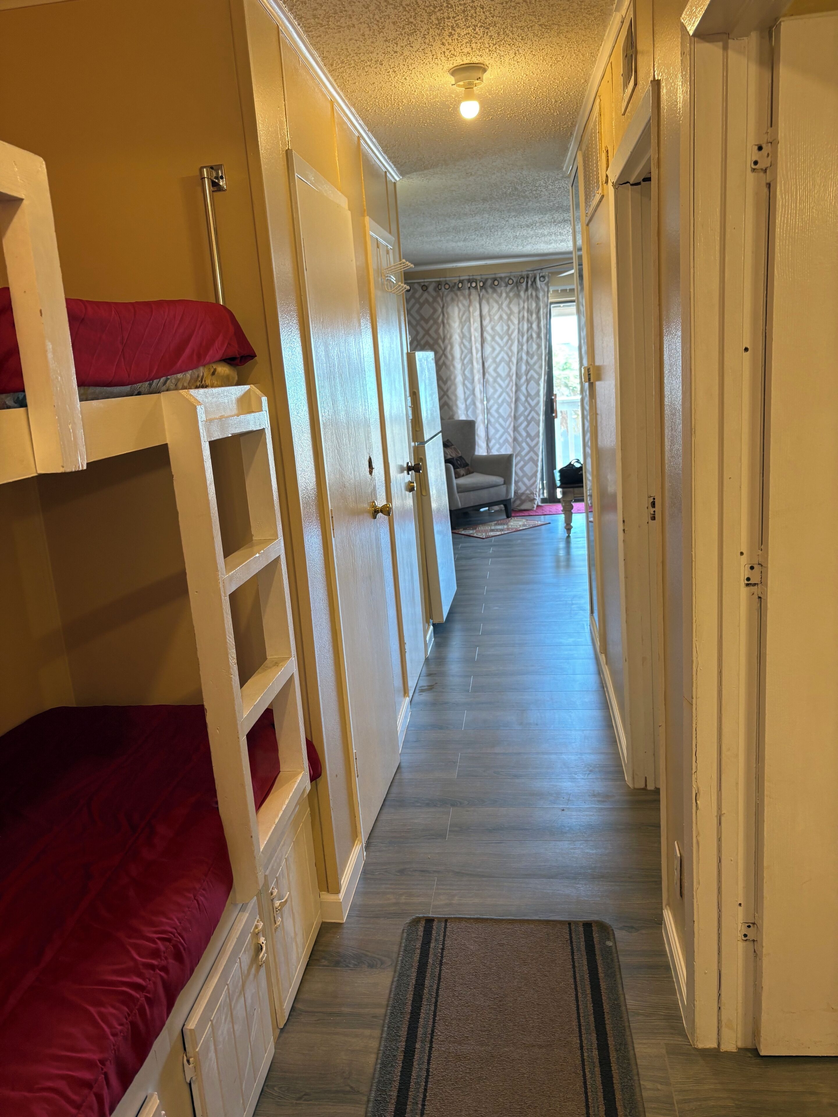 A narrow hallway with bunk beds on one side and a door on the other.