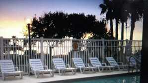 A swimming pool with lounge chairs and a fence. - Steps from the Beach, sun, surf and boardwalk! (Corpus Christi)