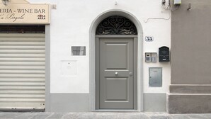 Ein Gebäude mit geschlossenem Rollo, einer Tür mit dekorativem Bogen und einem Schild mit der Aufschrift 'PERGOLA - WINE BAR'.