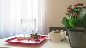 Ein Tisch mit einer rosa Tablett, zwei Gläsern, einer Oliven-Schale, einem Brotkorb und einer Blumentopf.