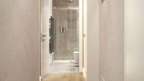 Ein Flur, der zu einem Badezimmer mit Duschkabine und Toilette führt.
