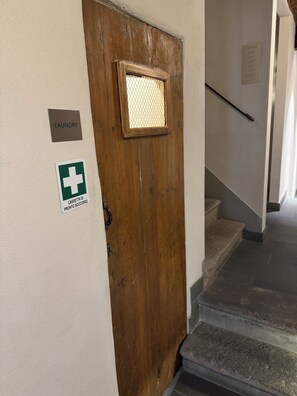 A wooden door with a mesh window, a sign for laundry, and a first aid kit sign.