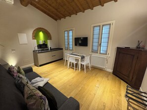 A compact living space with a kitchenette, a dining area, a sofa, and a television.