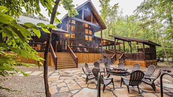 A rustic cabin with a stone patio, outdoor seating, and a fire pit.